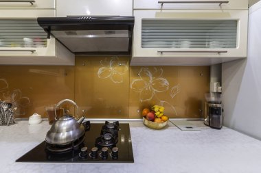 Modern mutfak sarı iç arka plan üzerine kaynar su üzerinde yanan gaz ile parlak paslanmaz çay çaydanlık çaydanlık soba.