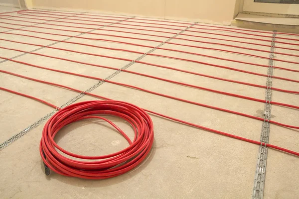 Heating red electrical cable wire roll on cement floor copy space background. Renovation and construction, comfortable warm home concept.