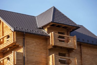 Yakın çekim yeni modern ahşap sıcak ekolojik yazlık ev top kahverengi çatısı shingled ve mavi gökyüzü arka plan üzerinde ahşap karosiyeri detayını. Profesyonelce yapılan marangozluk ve inşaatı işi.