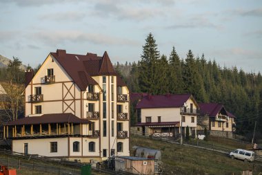 Mavi gökyüzünün altında Ladin Ağaçlar ve dağlar tepeler zemin üzerine Vinç ve yeni modern konforlu otel ev ekolojik kırsal alanda shingled çatılı bina ile şantiye.