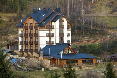 Yeni modern konforlu dört katlı otel ile bina bina, tavan Odalar bağlı ve Ladin üzerinde ekolojik kırsal alanda yüksek bacalar ağaçlar bahar ya da yaz arka plan.