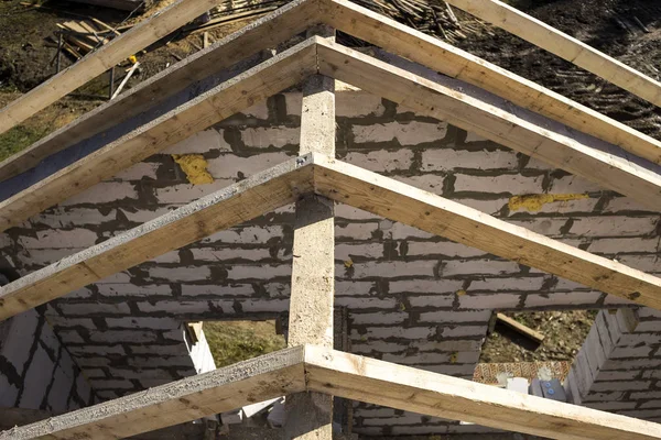 Top view of roof frame from wooden lumber beams and planks on walls made of hollow foam insulation blocks. Building, roofing, construction and renovation concept.