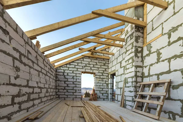 House interior under construction and renovation. Energy saving walls of hollow foam insulation blocks and bricks, ceiling beams and roof frame.