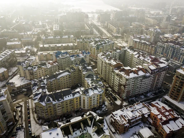 Aerial black and white winter top view of modern city center with tall buildings and parked cars on snowy streets. — Stock Photo, Image