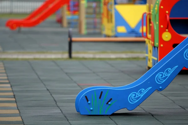 Luminosi scivoli colorati sul parco giochi della scuola materna con gomma morbida fl — Foto Stock