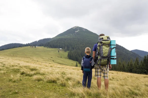 Vater und Sohn wandern mit Rucksäcken gemeinsam im Sommerberg — Stockfoto