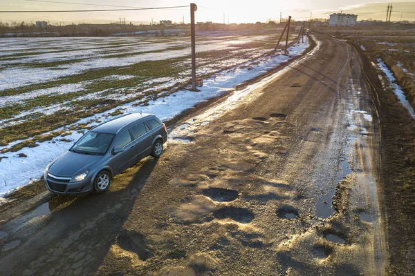 Aerial view of car moving along muddy rural road in bad conditio