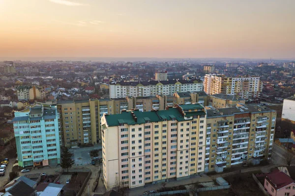 Top view of urban city landscape with tall apartment buildings and suburb houses on bright pink sky at sunrise copy space background. Drone aerial photography.