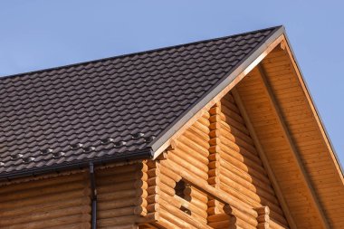 Yakın çekim yeni modern ahşap sıcak ekolojik yazlık ev top kahverengi çatısı shingled ve mavi gökyüzü arka plan üzerinde ahşap karosiyeri detayını. Profesyonelce yapılan marangozluk ve inşaatı işi.