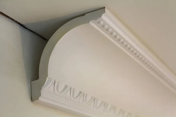 Detalle de primer plano de la decoración moldura blanca conectada con adhesivo de pegamento a la pared y el techo en la renovación y reconstrucción de la habitación interior . — Foto de Stock