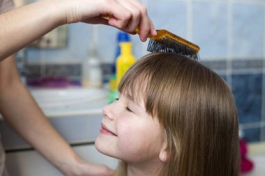 Sevimli çocuk kız uzun adil saç tarak fırça ile anne el