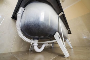 Yeni seramik küvet alt görünümü ışık banyo üzerinde arka plan döşer. Tesisat ve sıhhi tesisat kavramı.