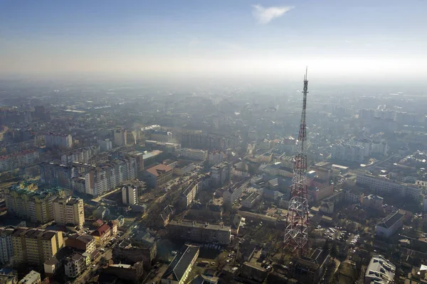 Aerial view of modern city urban foggy landscape with tall television tower on bright blue sky copy space background at dawn. Drone photography.
