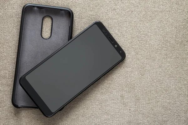 Nowy czarny nowoczesny telefon komórkowy i plastikowy futerał na białym tle — Zdjęcie stockowe