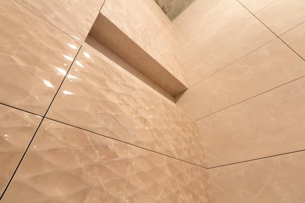 Úhlový pohled na koupelnu nebo záchod s lehkým béžovou geometrickou mozaikou, instalované na stěnách a cementovém stropu. Koncepce konstrukčních, konstrukčních a dlaždných konstrukcí. — Stock fotografie