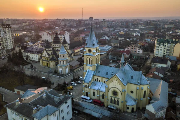 Luchtfoto van de stad bij zonsopgang of zonsondergang. Stedelijk landschap met kerk domes, geparkeerde auto's, hoge gebouwen op heldere roze hemel bij zonsondergang achtergrond. — Stockfoto