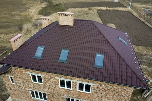 Aerial top view of building steep brown shingle roof, brick chim