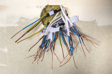 Elektrik bağlı tel beyaz duvar yuvadan çıkıntılı maruz. Elektrik Tesisatı yükleme. Bitirme işleri yenilenmiş daire.
