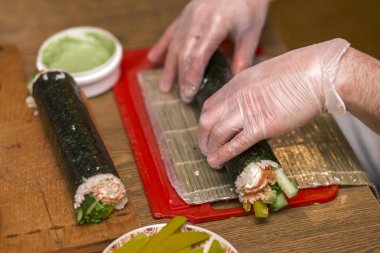 Suşi ve rulo yapma işlemi. Adam Şef Close-Up pr eller