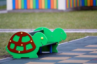 Parlak renkli komik bankta kreş Bahçesi yumuşak kauçuk zemin parlak güneşli yaz gününde ile. Çocuk aktiviteleri ve Rekreasyon açık havada.