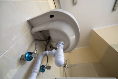 Bottom view of new white washbasin sink connected to sewer on ba clipart