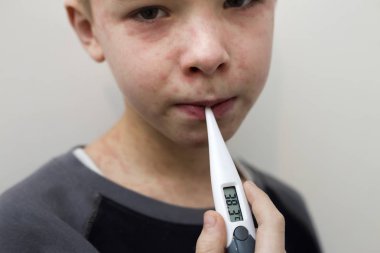 Portrait of sick sad boy child with thermometer having fever suf clipart