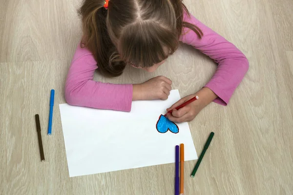 Dziecko dziewczyna rysunek z kolorowych ołówków kredki serce na białym — Zdjęcie stockowe