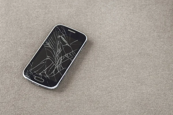 Черный старый мобильный телефон с треснувшим экраном на светлой ткани копировальный спак — стоковое фото