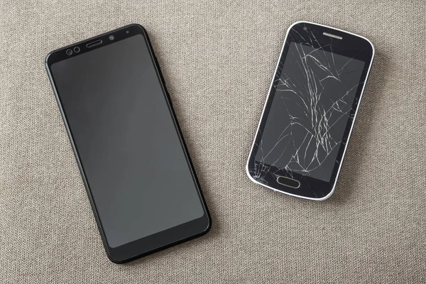 Comparação de dois telefones celulares pretos, celular antigo com cracke — Fotografia de Stock