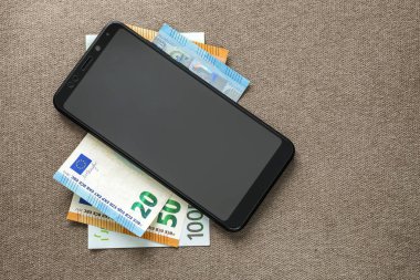 Kopya alanı doku arka plan üzerinde para euro banknotlar yeni siyah modern dijital cep telefonu. Gadget konseptini kullanarak modern teknoloji, iletişim ve çevrimiçi ticaret.