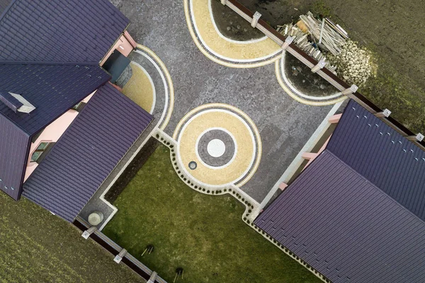 Vista superior aérea do telhado da telha da casa no fundo do gramado verde e pátio pavimentado colorido com padrão abstrato geométrico. Obras de telhadura, reparação e renovação . — Fotografia de Stock