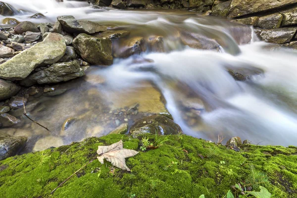 Rychle tekoucí proud řeky s hladkým hedvábným vody padající z b — Stock fotografie