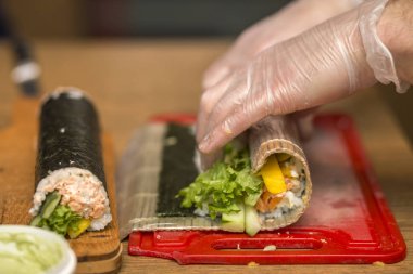 Suşi ve rulo yapma işlemi. Adam Şef Close-Up pr eller