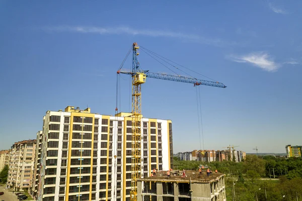 Apartamento ou escritório edifício alto em construção. Trabalhando construtores e guindastes torre no céu azul brilhante cópia espaço fundo. — Fotografia de Stock