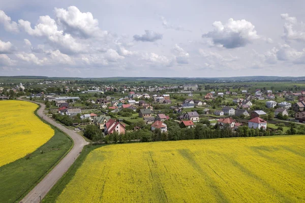 Vista aérea de la carretera terrestre en campos verdes con colza en flor — Foto de Stock