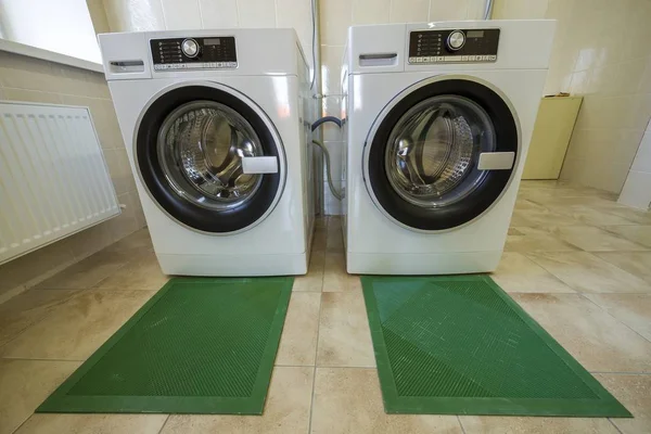 Современные новые промышленные стиральные машины в чистой кафельной ванной комнате o — стоковое фото