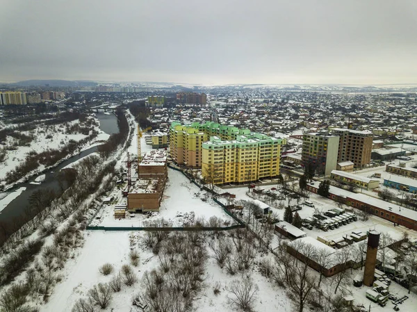 Aerial vintern ovanifrån av moderna utveckla staden förort område med höga byggnader, parkerade bilar och konstruktion kranar. Urbana stadsbilden på blå himmel kopia utrymme bakgrund. — Stockfoto
