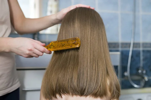 Sevimli çocuk kız uzun adil saç tarak fırça ile anne el — Stok fotoğraf