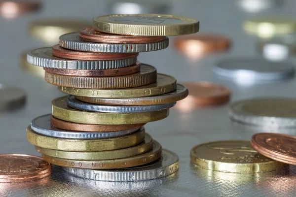 Duas pilhas de moedas brilhantes diferentes tamanhos e cores empilhados desigualmente um no outro em fundo abstrato azul borrado colorido. Conceito de poupança de dinheiro e risco financeiro . — Fotografia de Stock