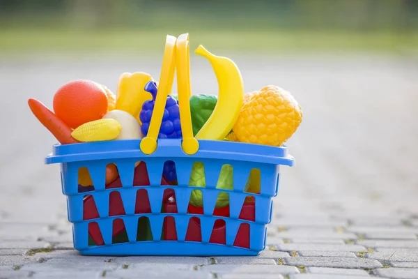 Bright plastic colorful basket with toy fruits and vegetables ou