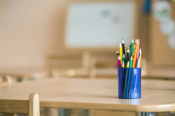 Wooden colorful drawing pencils arranged in plastic jug on light — Stock Image Wooden colorful drawing pencils arranged in plastic jug on light Stock Photo