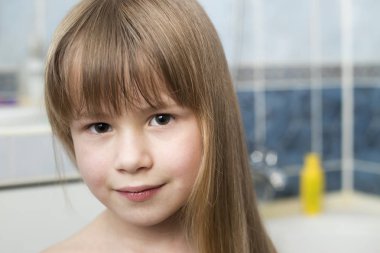 Güzel gözlü çocuğun gülümseyen kız yüz, portre ve uzun sarı saçlar banyo bulanık arka plan üzerinde ıslak.