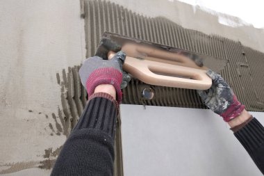 Duvara seramik fayans koyan işçi elleri.