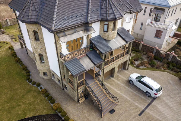 Novo carro branco caro estacionado no pátio bem cuidado pavimentado com gramado verde, arbustos decorativos e cerca de tijolo de casa grande dois andares. Conceito de luxo e prosperidade . — Fotografia de Stock