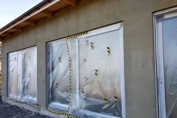 Janelas de uma casa em construção coberta com pl protetora — Fotografia de Stock