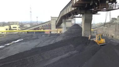 Buldozer çekici termoelektrik santralinin ikmal sahasında siyah kömür topluyor..