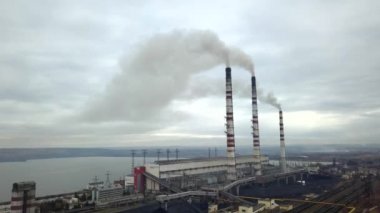 Kömür santralinden gelen gri dumanlı yüksek baca borularının havadan görüntüsü. Fosil yakıtla elektrik üretimi.