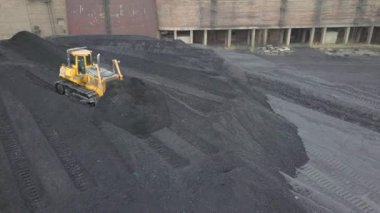 Buldozer çekici termoelektrik santralinin ikmal sahasında siyah kömür topluyor..