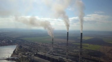 Kömür santralinden gelen gri dumanlı yüksek baca borularının havadan görüntüsü. Fosil yakıtla elektrik üretimi.