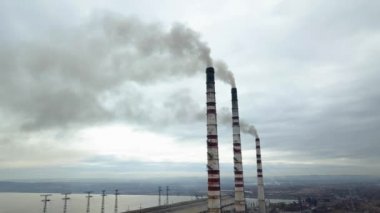 Kömür santralinden gelen gri dumanlı yüksek baca borularının havadan görüntüsü. Fosil yakıtla elektrik üretimi.